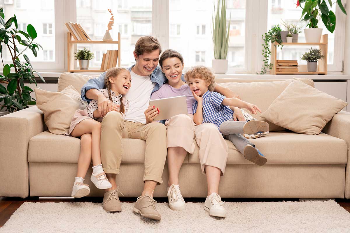 young joyful casual family Father, Mother, and two kids couple sitting and watching Gomlaza Store offers in home accessories.