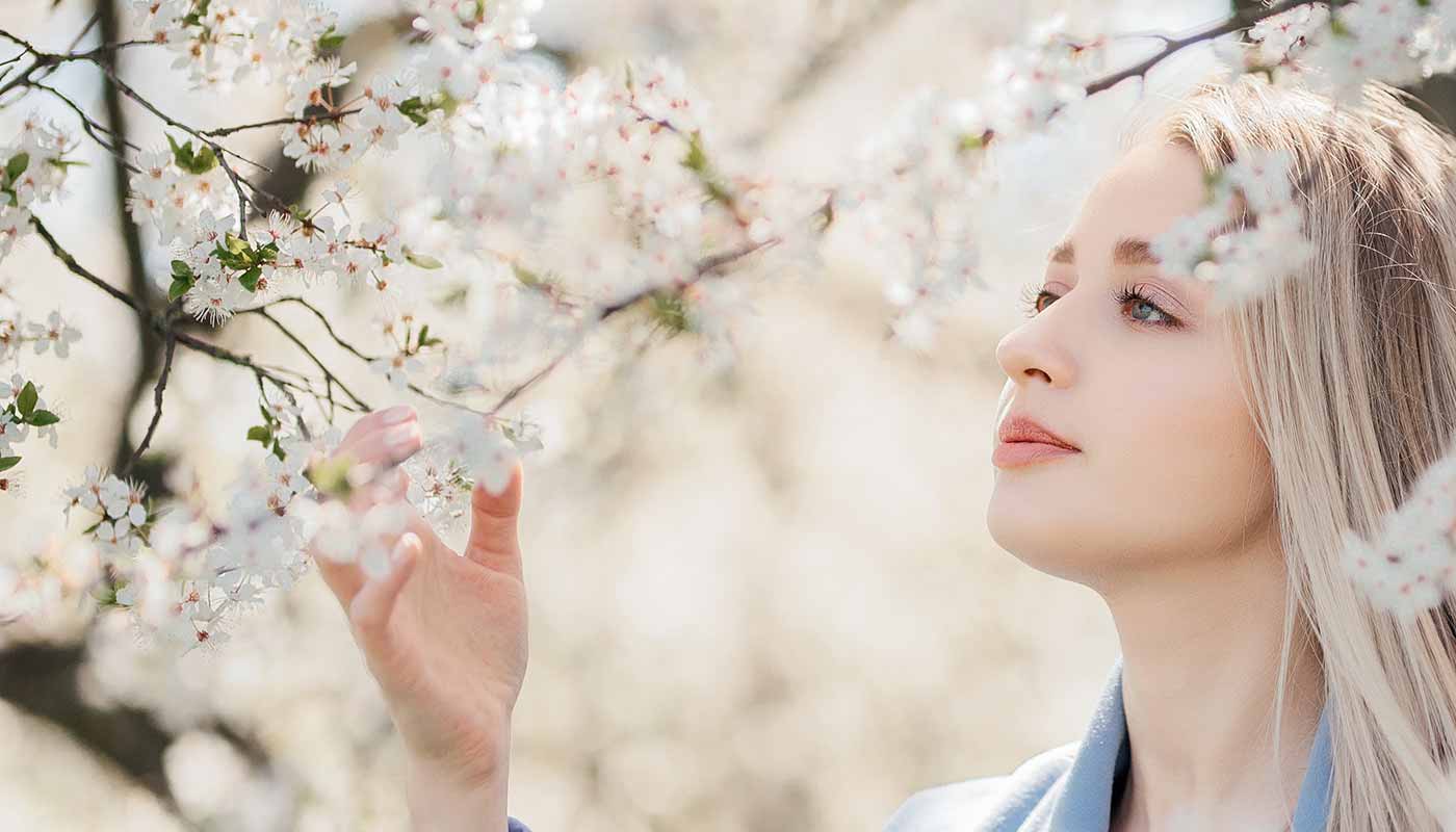 A-beautiful-blonde-young-woman-caresses-the-branches-and-flowers-of-the-white-apple